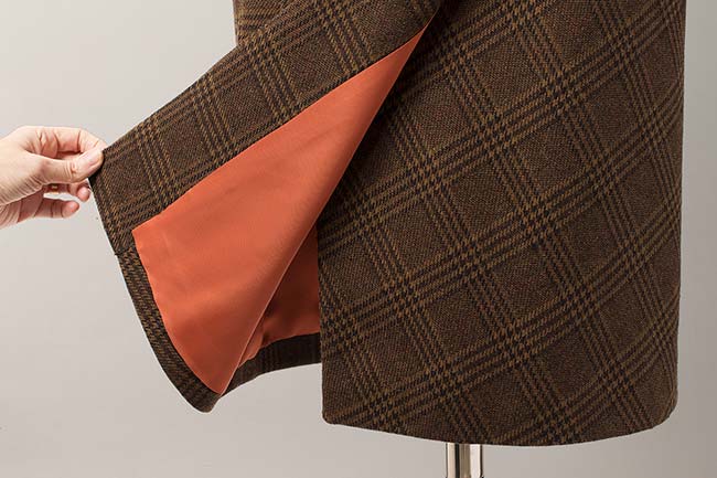 Forro naranja en contraste con la tela de cuadros de la falda.